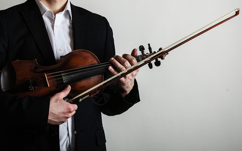 艺术和家紧的男手小提琴拿着灰色的小提琴古典音乐工作室拍摄图片