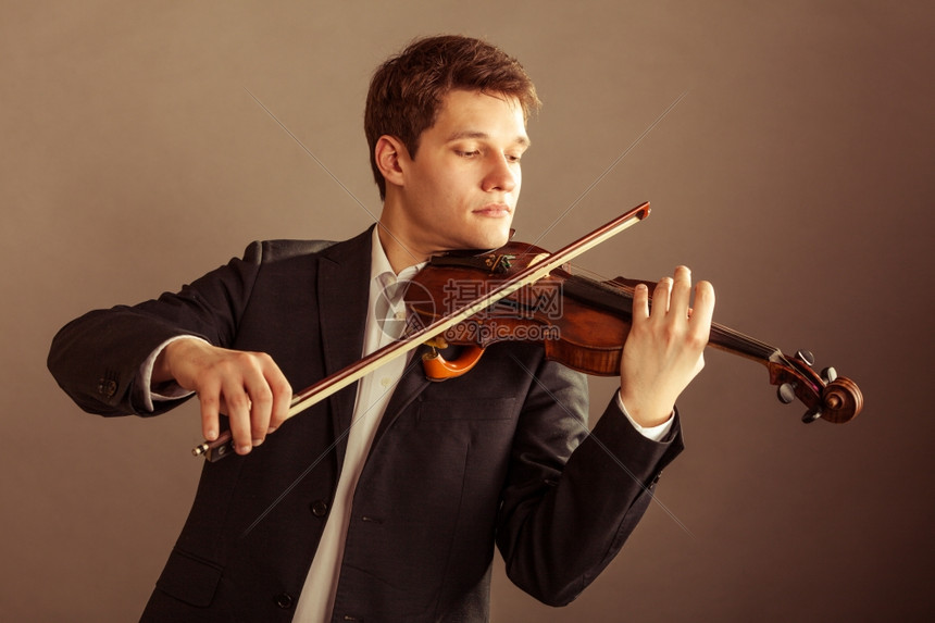 年轻优雅的小提琴家手在棕色古典音乐演播室拍小提琴