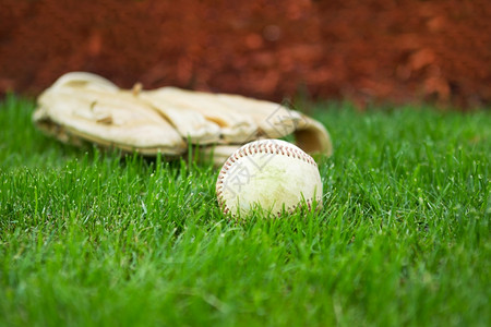 在自然草场背景上戴手套的旧棒球横向近照图片