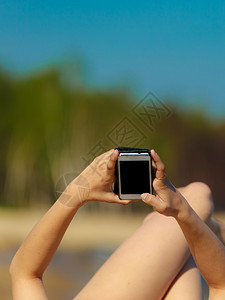 暑假女手紧闭孩晒太阳在海滩上黑年轻女在海边用手机放松夏天图片