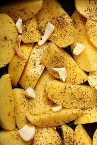 生皮土豆加香料黄油切片准备作为背景烤图片