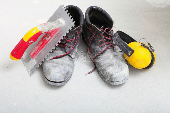 房屋翻新建筑设备肮脏的工作靴和建筑地的黄色保护噪音罩图片