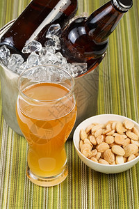 一张金啤酒在高玻璃杯中盐坚果在小碗里瓶装啤酒在冰桶里图片