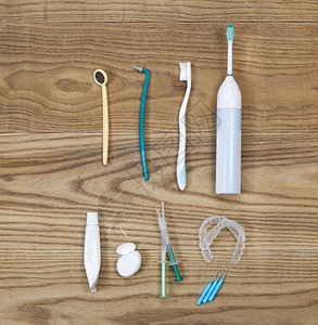 在老木板上放置的牙科维修工具包括手牙刷摘子白色托盘凝胶镜子牙膏管和电刷图片