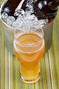 高杯装满彩色啤酒和在冰桶里瓶啤酒的彩色图片