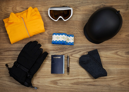 固定木板上基本滑雪和板配件的俯视图包括头盔护目镜手套汗衫头带羊毛袜和护照图片