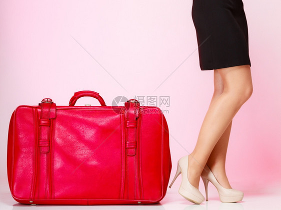 侧视女高跟鞋和红皮箱在粉色背景上优雅的女士在航行中旅概念图片
