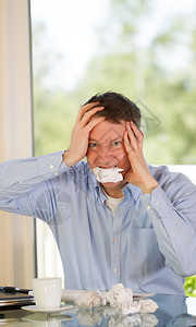 成年男子的垂直图像显示压力在家工作时用一瓦纸咬而光从窗中打入背景图片