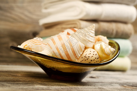 玻璃碗中贝壳的横向眼部视图在生锈木上背景有干净的堆叠毛巾图片