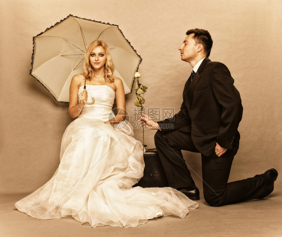结婚日浪漫已夫妇金发新娘的肖像配着雨伞和美新郎的给女孩送玫瑰图片