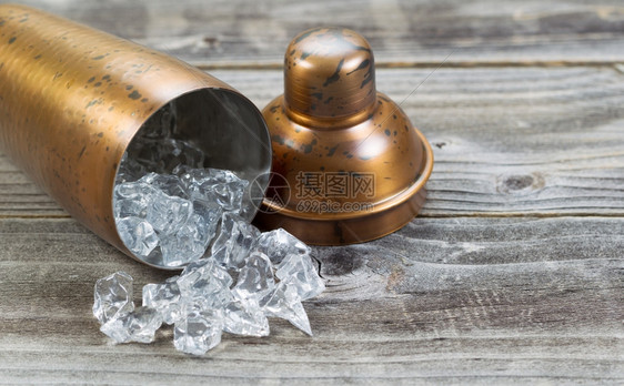 旧金属饮料搅拌器它与压碎的冰流出到生锈的木头上图片