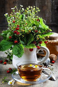 配有草药茶和蜂蜜的野草莓花束生物食或健康概念图片