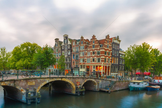 荷兰阿姆斯特丹运河桥梁和典型房屋船只和自行车的黄昏城市景象图片