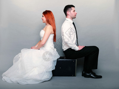 幸福的已婚夫妇红发新娘和郎的肖像坐在旧手提箱上坐在后面的工作室拍摄灰色背景蜜月和旅行图片