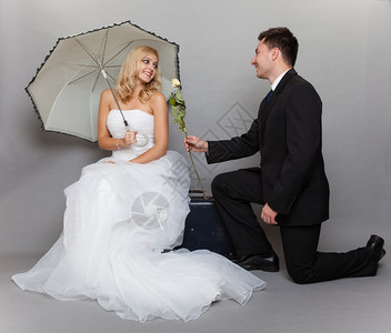 今天是结婚日浪漫已夫妇金发新娘的肖像配着雨伞的金发新娘和深色郎给女孩送玫瑰图片