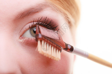 装饰美容程序和化妆概念关闭女部分面化妆细节使用梳子在应mascara之后分别抽鞭子长的睫毛图片