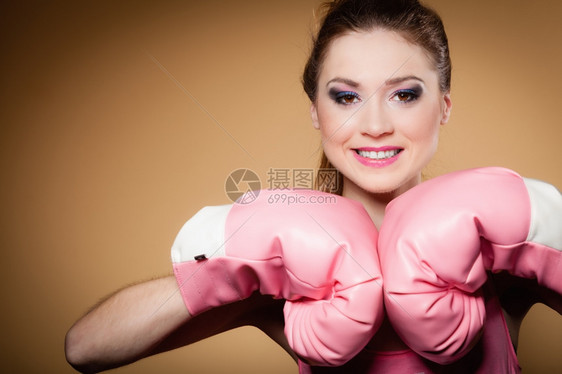 运动女拳击模特身着大有趣的粉红手套玩运动拳击演播室射棕色背景图片