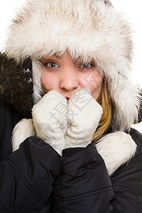 冬假衣着温暖的冷冻女孩戴着毛帽的年轻女人冷手冰地用白色的隔绝气息取暖图片