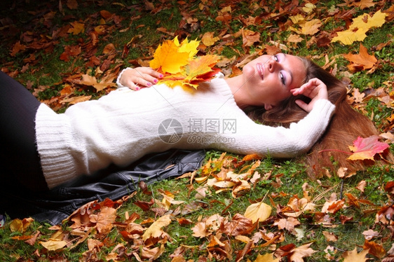女子手握着秋叶躺在草地上图片