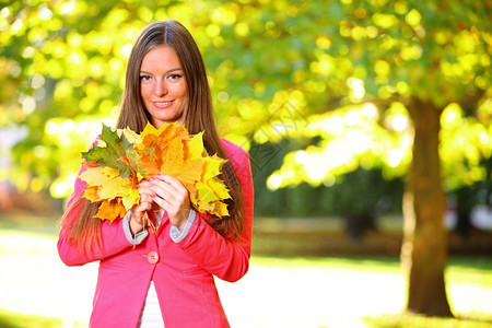 有秋叶的年轻女子手握着秋叶图片