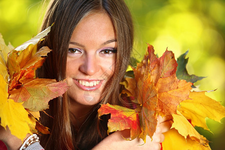 有秋叶的年轻女子手握着秋叶图片