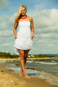 假期旅行和自由概念穿着白裙子的漂亮女孩在海滩上散步年轻女在海边放松图片