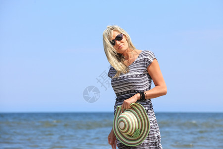 在海滩上戴帽子的成年女享受暑假图片