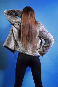 穿着毛皮大衣长头发的年轻时尚女子背影蓝色景图片