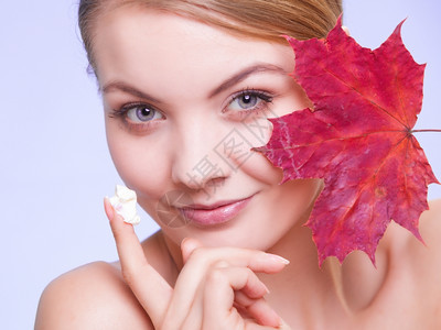 皮肤习惯年轻女表情紫外线上叶子是红毛皮的象征女孩用湿润奶油照顾干燥的皮肤美容治疗图片