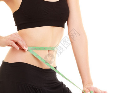 关闭瘦的年轻女孩肚子用绿度胶带将她的腰围隔离在白色上图片