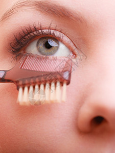 装饰美容程序和化妆概念关闭女部分面化妆细节使用梳子在应mascara之后分别抽鞭子长的睫毛图片