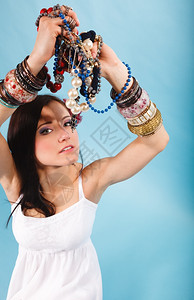 夏天风流的美年轻女子有很多首饰珠在手蓝色背景图片