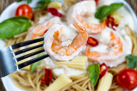 持有单虾的不锈钢叉宏观景阿尔弗雷多帕斯塔晚宴放在白盘上背景的图片