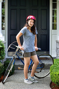年轻女孩的垂直形象展望未来同时与背景家庭骑自行车一起休息图片