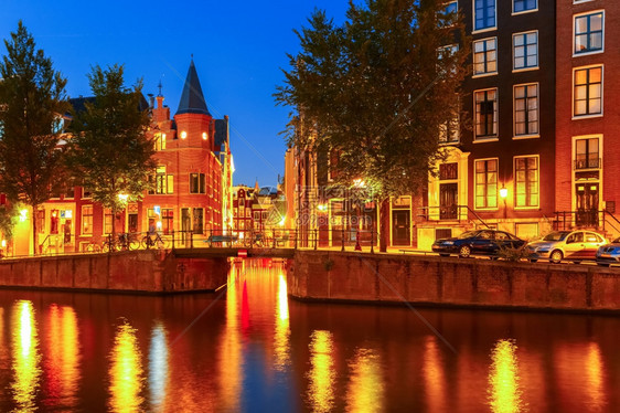 荷兰阿姆斯特丹运河桥梁典型房屋和自行车的夜景图片