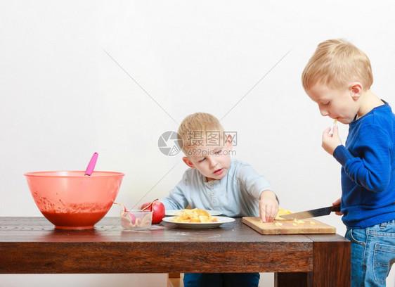 金发男孩用菜刀切果苹图片