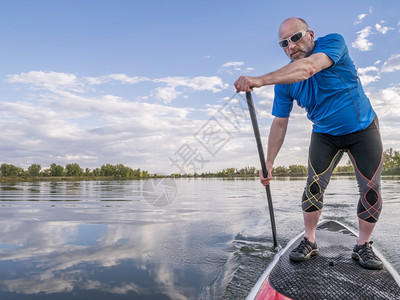 在科罗拉多州平静湖夏末的悬浮板SUP上享受锻炼的高级男护板图片