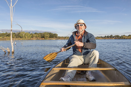 在科罗拉多州林斯堡河滨池塘自然区独木舟湖上享受晨日的老年男图片