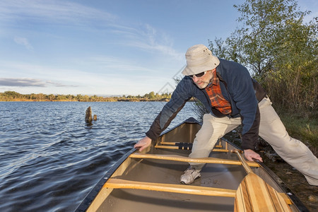在科罗拉多州柯林斯堡的河滨池塘自然水域湖上用高级男发射独木舟进行上午划船作业图片