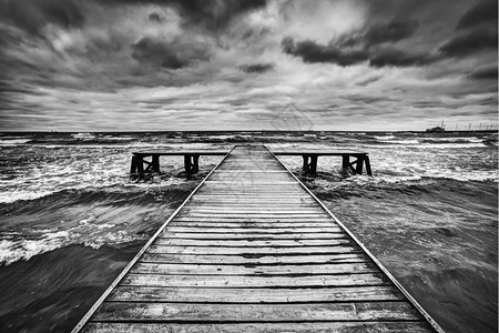 古老的木制码头大海风暴期间黑暗而沉重的云层戏剧天空黑色和白的天空图片