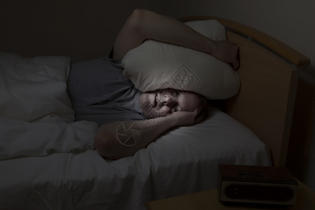 成年男子头顶枕头眼睛睁大失眠无法入睡图片