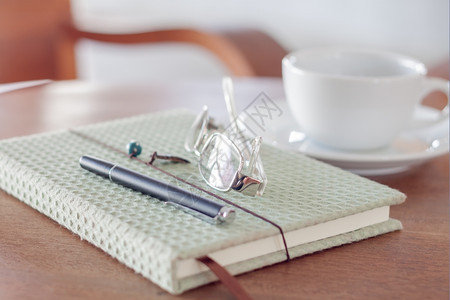 纸笔记本眼镜和木制桌上的白咖啡杯股票照片图片