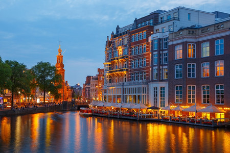荷兰阿姆斯特丹运河桥梁和蒙托伦塔的夜间城市景象图片