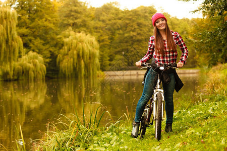 女青年在秋天公园户外骑着自行车停顿休息图片