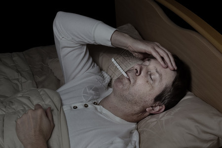 成年男子的横向形象高发躺在床上测试体温图片