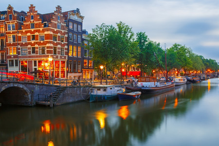 荷兰阿姆斯特丹运河桥梁和典型房屋船只和自行车的夜间城市景象图片