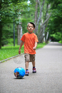 男孩玩球踢在户外公园向球跑图片
