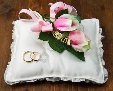 白色背景的结婚戒指和粉红玫瑰图片