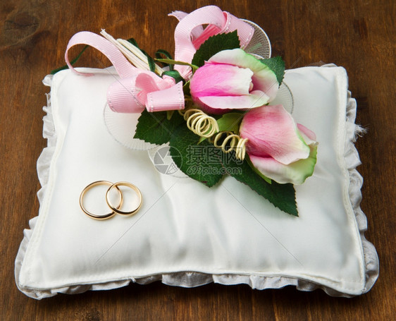白色背景的结婚戒指和粉红玫瑰图片