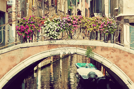 意大利威尼斯一座有鲜花的桥在老威尼斯建筑的狭小运河上图片